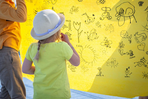 Auf dem Bild sieht man ein Kind, wie es auf ein gelbes Plakat schaut