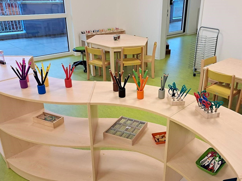 Foto vom Innenbereich des FRÖBEL-Kindergartens Heinrich der Löwe in Braunschweig. Raum mit niedrigem Regal, auf dem Stifte nach Farben sortiert stehen.