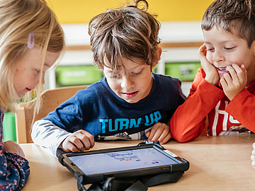 Kinder beim Umgang mit einem Tablet (© Fröbel e. V. Foto: Tom & Franziska Werner)