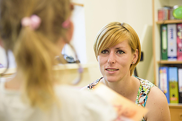 Mit Kindern über Corona sprechen: Erzieherin hört einem Kind aufmerksam zu