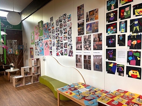 Ausstellungsraum mit einer Wand voller Fotografien, Zeichnungen und Collagen