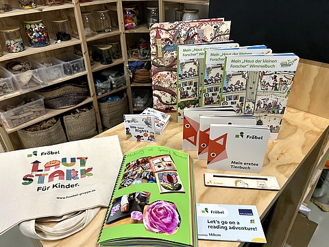 Materialien für den internationalen Austausch liegen auf einem Tisch: Kinderzeichnungen, Bücher, Briefe und Informationsmaterialien in einem Ringordner