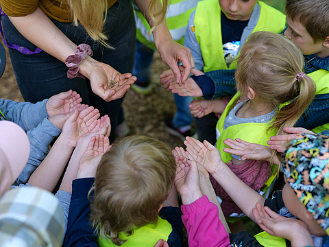 Mehrer Kinder stehen mit geöffneten Hände in einem Kreis
