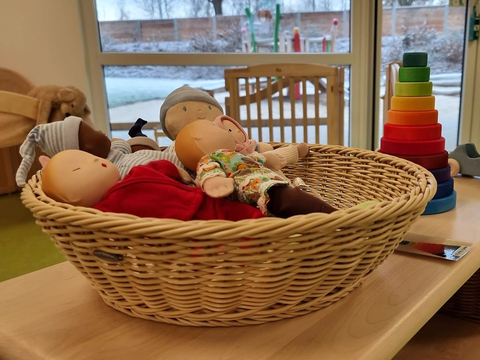 Foto vom Innenbereich des FRÖBEL-Kindergartens Heinrich der Löwe in Braunschweig. Detailaufnahme von einem Korb in dem Puppen mit verschiedenen Hautfarben liegen.