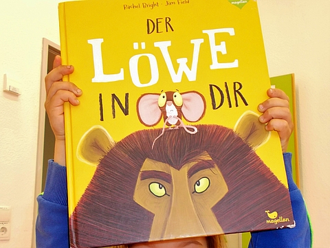 Kind hält das Buch "Der Löwe in dir" in der Hand
