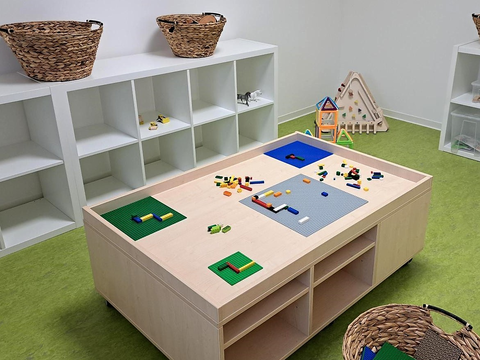 Foto vom Innenbereich des FRÖBEL-Kindergartens Heinrich der Löwe in Braunschweig. Bauraum mit verschiedenen Baumaterialien und Lego-Tisch mit Platten und Steinen.