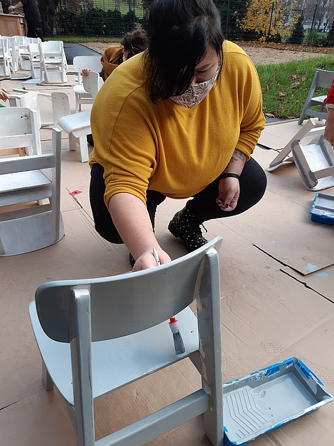 Letzte Handgriffe kurz vor der Eröffnung: Stühle aus einer Kindergarten-Auflösung erhalten neuen Lack - ganz im Sinne des Nachhaltigkeitskonzepts. (Fotocredits: FRÖBEL e.V.)