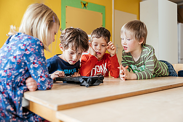 Digitaler Vorlesetag im Live-Stream: Kindergarten-Kinder schauen gemeinsam auf ein Tablet