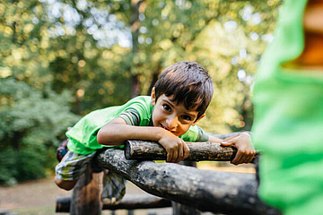 Ein Junge lehnt sich über einen Holzstamm. 
