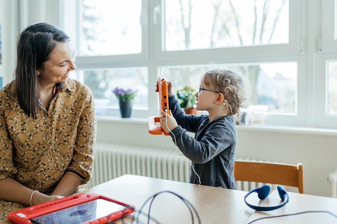 Ein Kind macht mit einem Tablet ein Foto von seiner Erzieherin