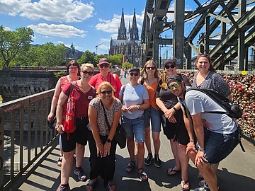 Deutsche und isländische Pädagog*innen auf Sightseeing-Tour in Köln. Sie posieren auf der Deutzer Drücke. Im Hintergrund ist der Kölner Dom. 