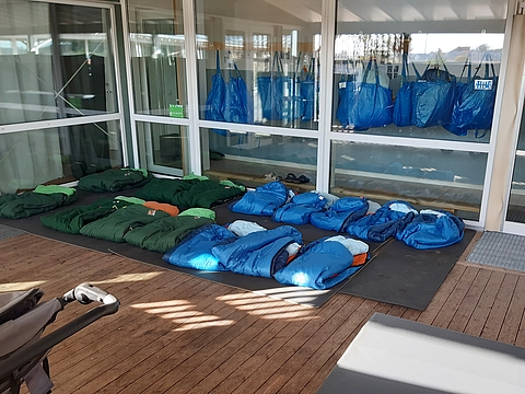 Foto einer überdachten Terrasse, auf der viele Schlafsäcke für den Mittagsschlag der Kinder vorbereitet sind