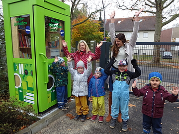 Juhu, die Kinder-Bücherbox ist eröffnet! Koordinatorin Kerstin Rosenfeldt (links hinten) und Einrichtungsleiterin Natascha Winterfeldt (rechts) mit begeisterten Kindern. Foto: FRÖBEL e.V.