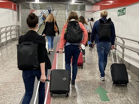 Mehrere Personen des Teams Personalgewinnung ziehen ihre Koffer durch einen unterirdischen U-Bahn-Gang in Madrid. Die Gruppe bewegt sich in Richtung einer Rolltreppe.