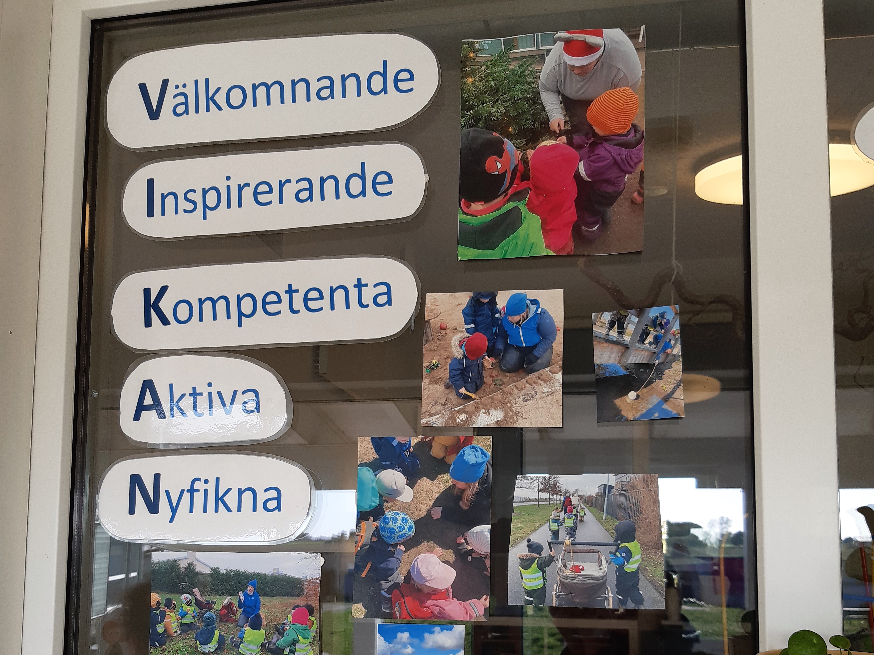 Foto von Wortkarten und Fotos auf einer Fensterscheibe. Die Wörter heißen übersetzt Willkommen Inspirierend Kompetent Aktiv Neugierig